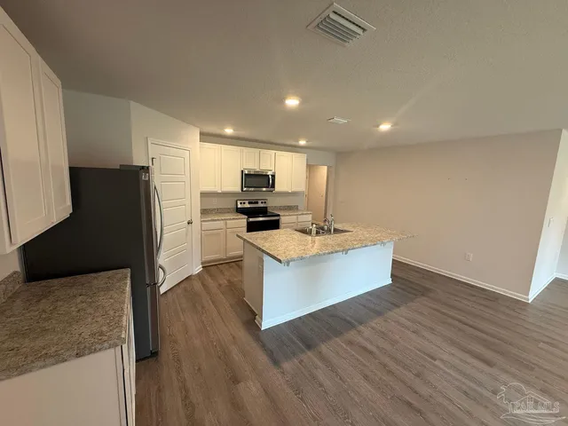 a kitchen with kitchen island white cabinets and stainless steel appliances