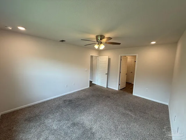 a view of an empty room with a chandelier fan