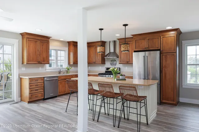 a kitchen with stainless steel appliances granite countertop a refrigerator a stove a sink dishwasher and wooden cabinets with wooden floor