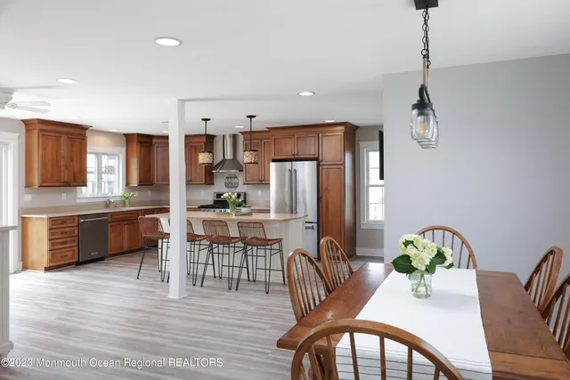 a kitchen with stainless steel appliances a dining table chairs refrigerator and cabinets