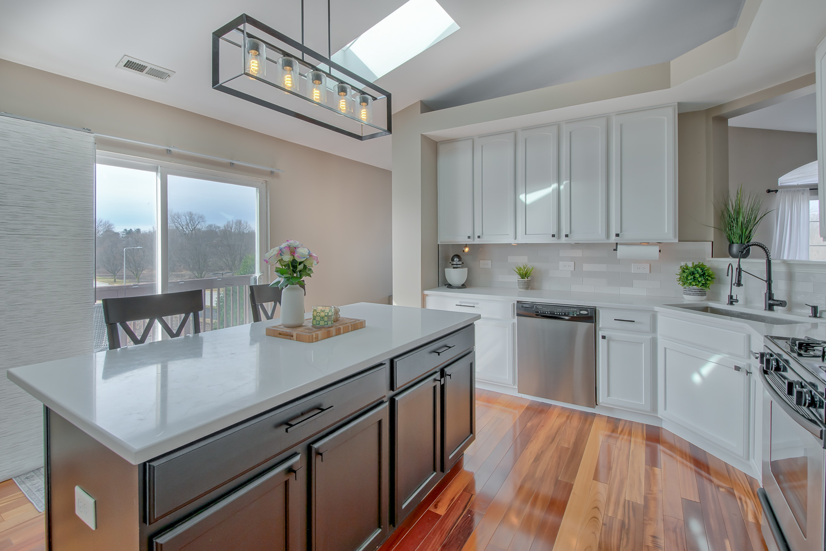 2305 Summerlin Drive Aurora, IL 60503 - Photo 8 of 22 a kitchen with a sink dishwasher a stove a microwave oven and a dining table with wooden floor