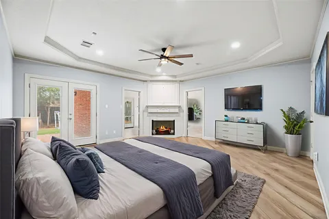 a bedroom with a large bed a flat tv screen and a chandelier