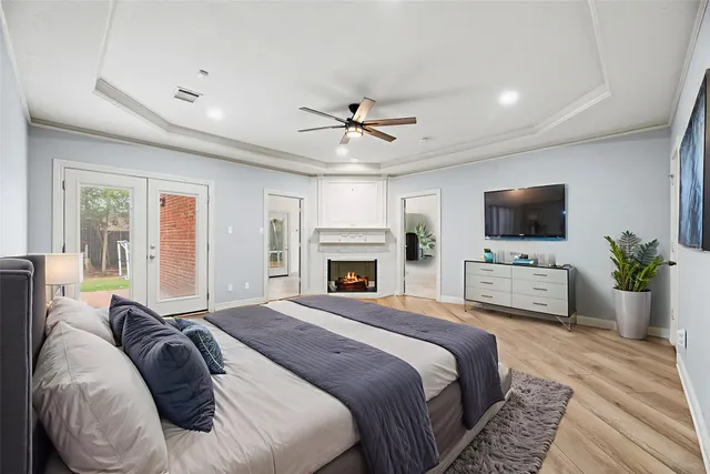 a bedroom with a large bed a flat tv screen and a chandelier