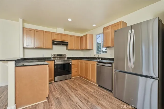 a kitchen with granite countertop a refrigerator stove top oven and sink