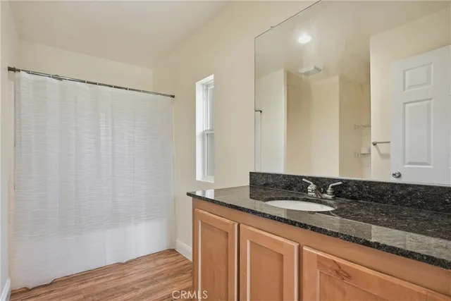 a bathroom with a granite countertop sink a mirror and a shower