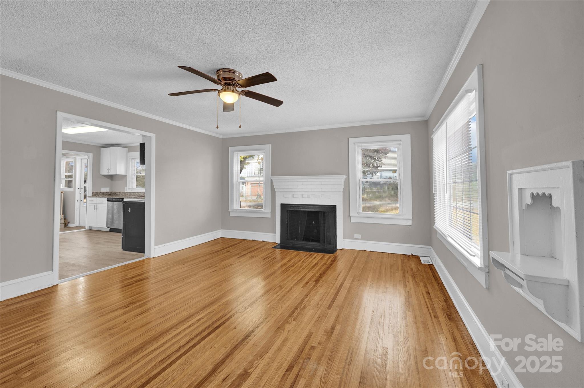 144 Robbins Street Southwest Concord, NC 28025 - Photo 6 of 29 a view of a livingroom with wooden floor a ceiling fan and windows