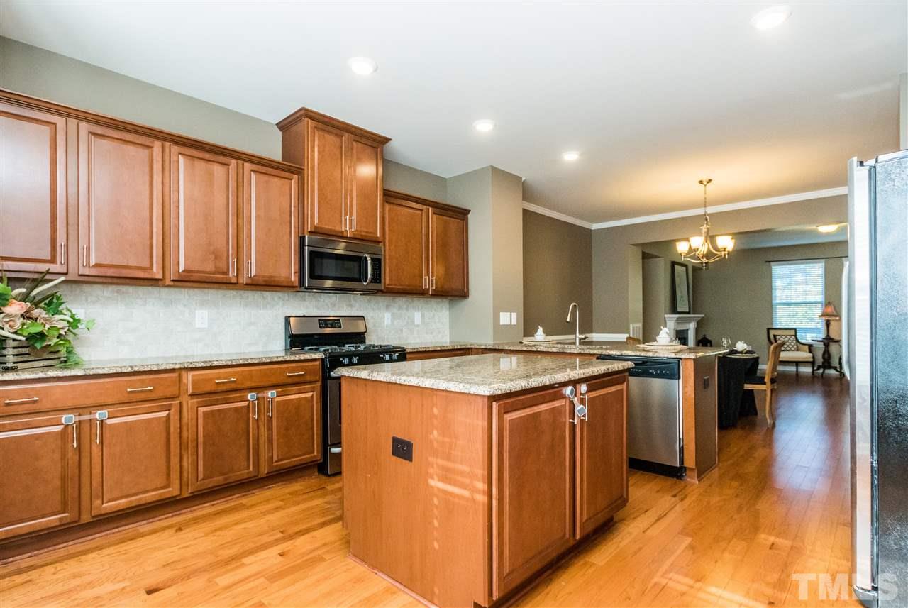 706 Edgewater Ridge Court Apex, NC 27523 - Photo 5 of 25 a kitchen with stainless steel appliances granite countertop a stove top oven a sink dishwasher and a refrigerator with wooden floor
