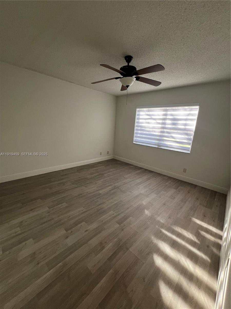 301 Cambridge Road, Unit 211 Hollywood, FL 33024 - Photo 22 of 33 an empty room with wooden floor ceiling fan and windows