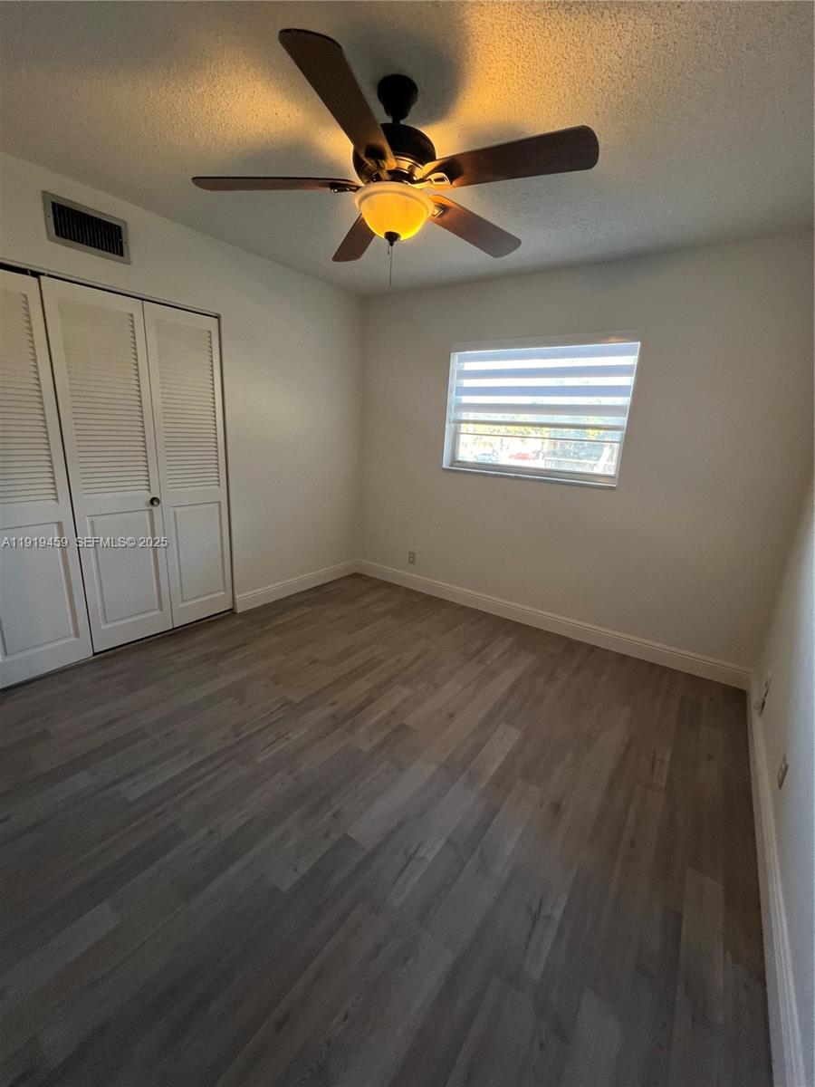 301 Cambridge Road, Unit 211 Hollywood, FL 33024 - Photo 32 of 33 an empty room with wooden floor chandelier fan and windows