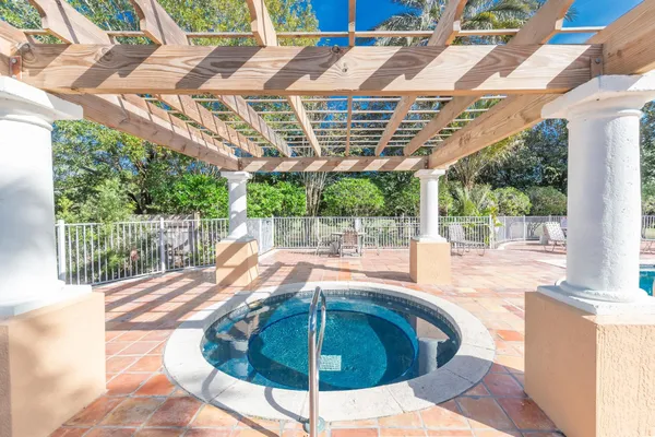 a outdoor view of a swimming pool with a patio and plants