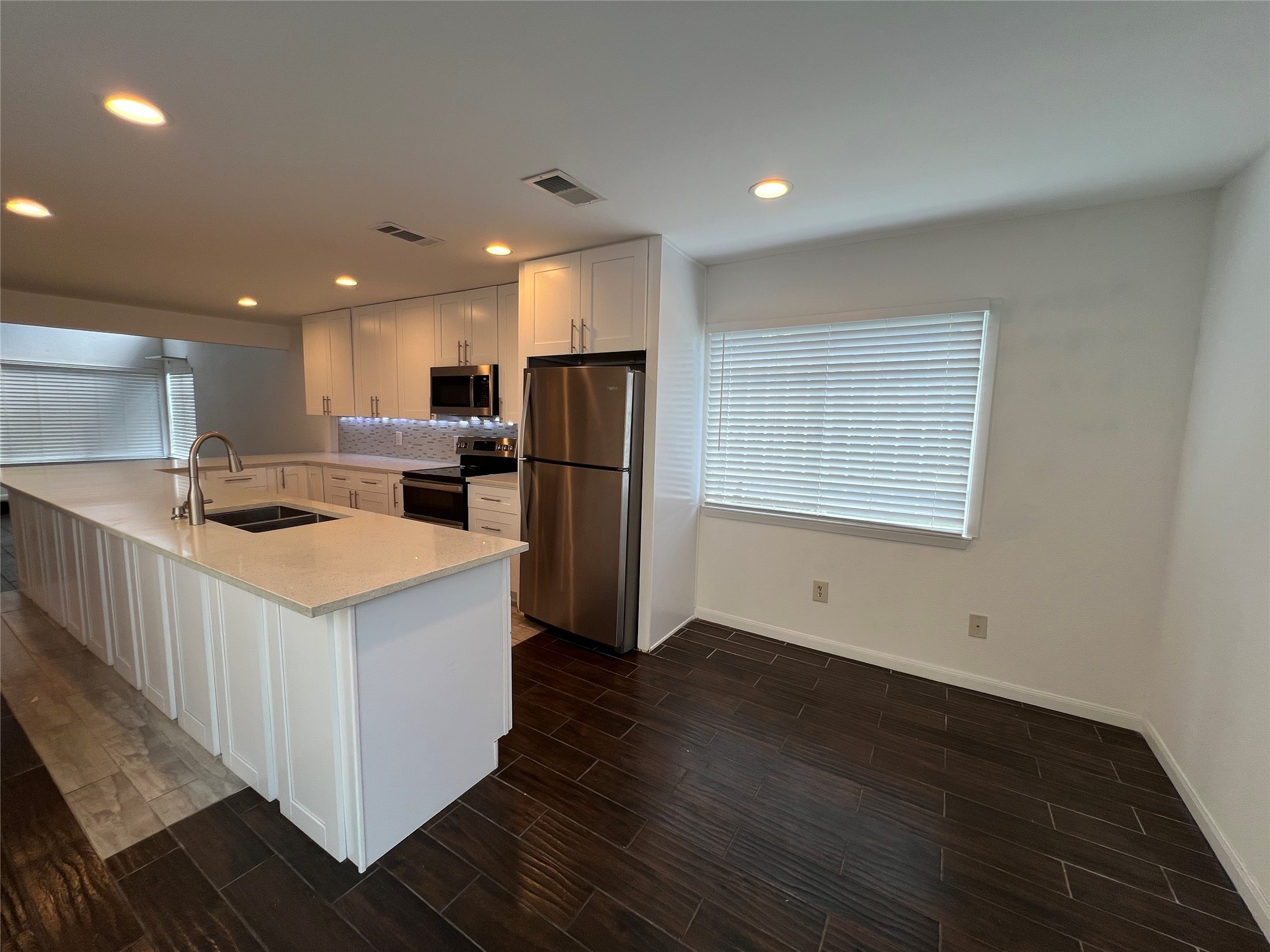 2372 Woodland Park Drive, Unit 121 Houston, TX 77077 - Photo 15 of 47 a kitchen with a refrigerator a sink dishwasher and a stove top oven with wooden floor
