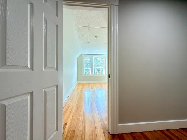 a view of a hallway with wooden floor and a window