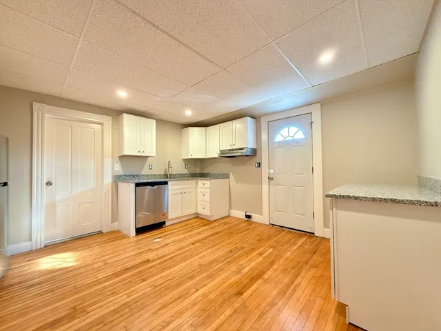 a open kitchen with white cabinets and wooden floor