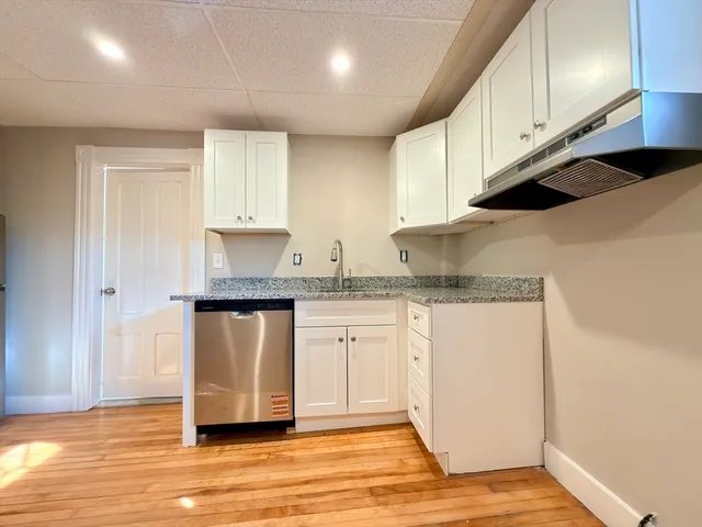 a kitchen with granite countertop a sink and white cabinets