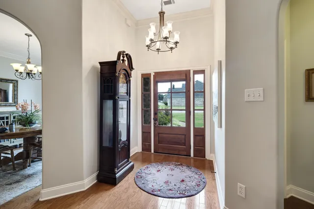 a view of a room with a chandelier and wooden floor