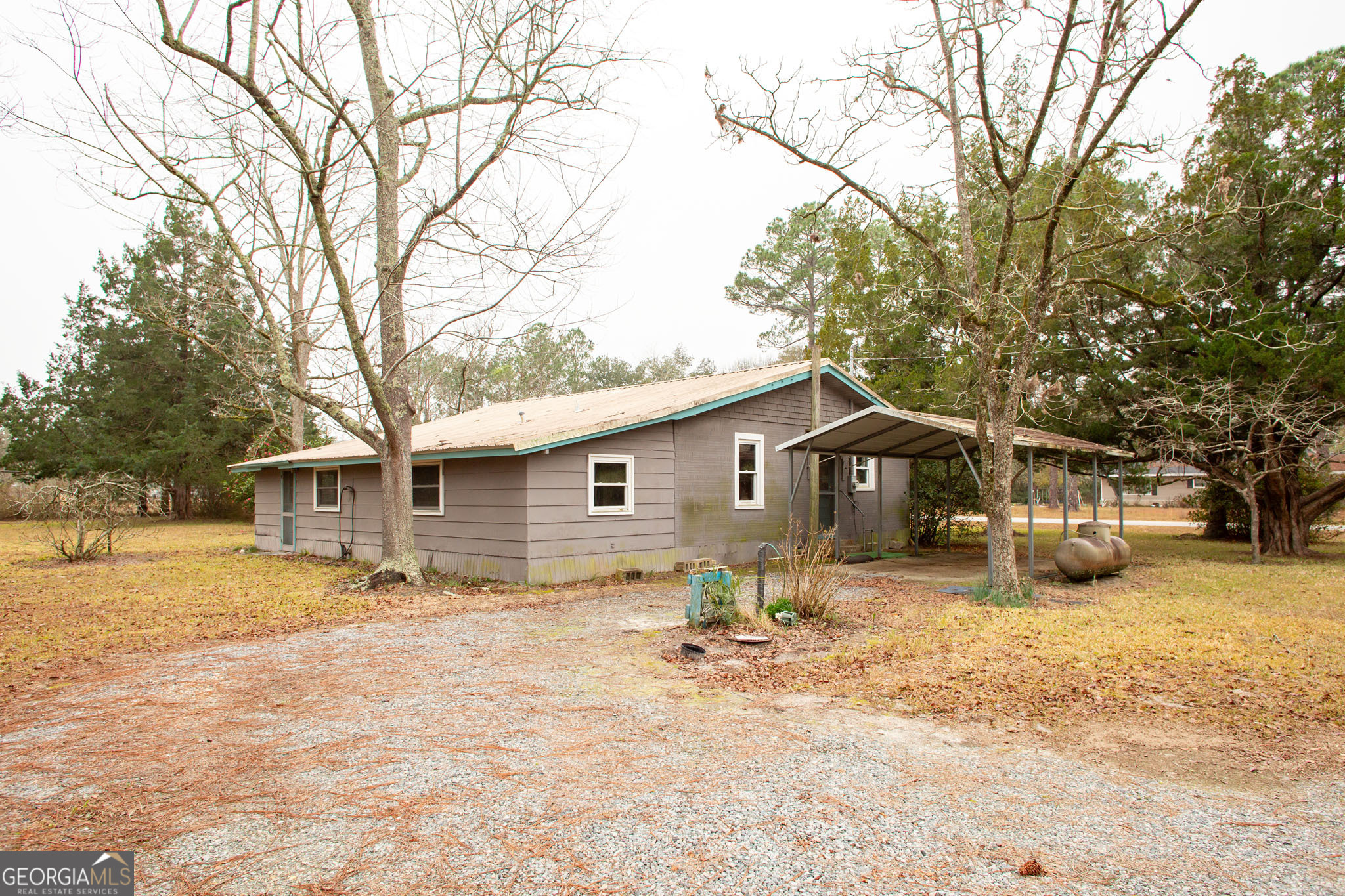 4618 Old Waltertown Road Waycross, GA 31503 - Photo 32 of 39 a backyard of a house with table and chairs under an umbrella