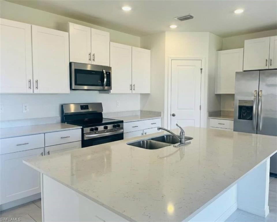 17536 Monte Isola Way North Fort Myers, FL 33917 - Photo 8 of 19 a kitchen with stainless steel appliances a stove a sink a microwave and cabinets