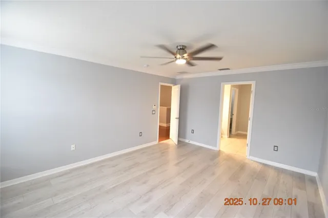 wooden floor in an empty room with a chandelier fan