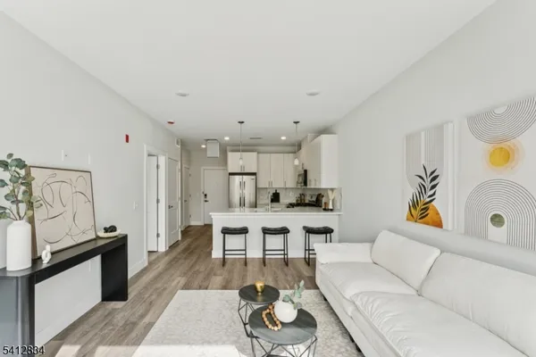 a living room with furniture a rug kitchen view and a table