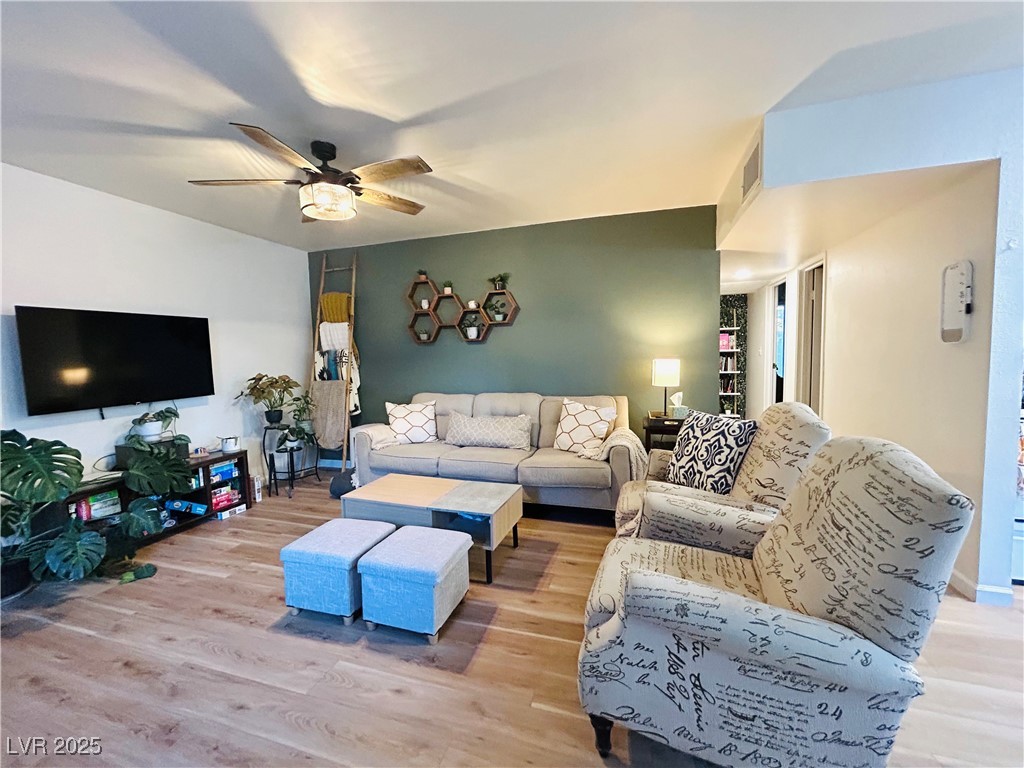 524 Fir Street, Unit 203 Boulder City, NV 89005 - Photo 1 of 7 This bright and airy living room boasts a modern ceiling fan and warm hardwood floors, creating an open and inviting atmosphere. The space is illuminated with natural light, enhancing its spacious and welcoming feel.