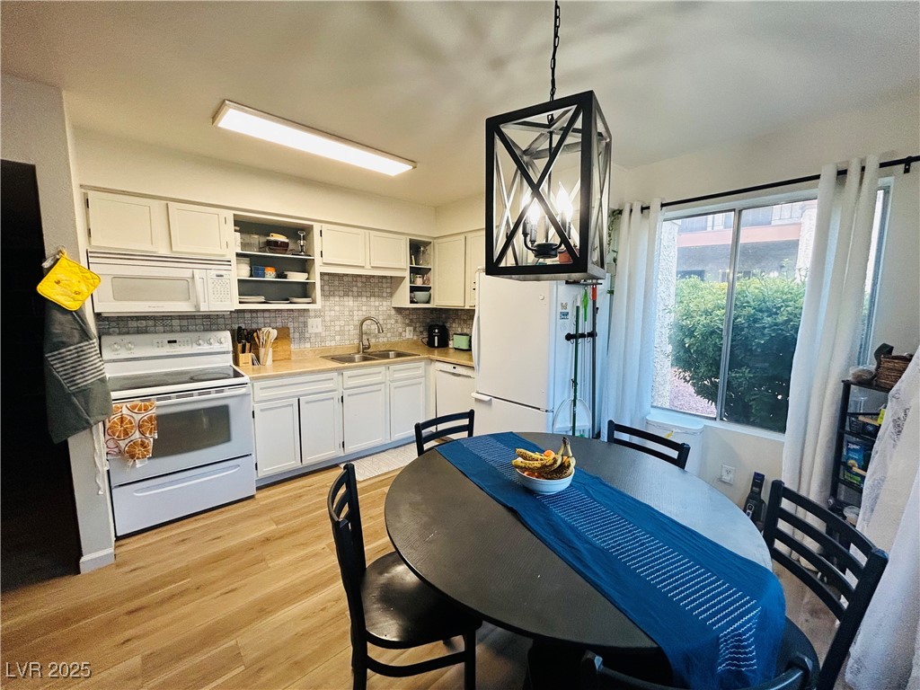 524 Fir Street, Unit 203 Boulder City, NV 89005 - Photo 3 of 7 This bright dining area features large windows with natural light, and warm hardwood floors, creating an inviting and airy space. A stylish pendant light adds a touch of elegance to the open layout adjacent to the kitchen.