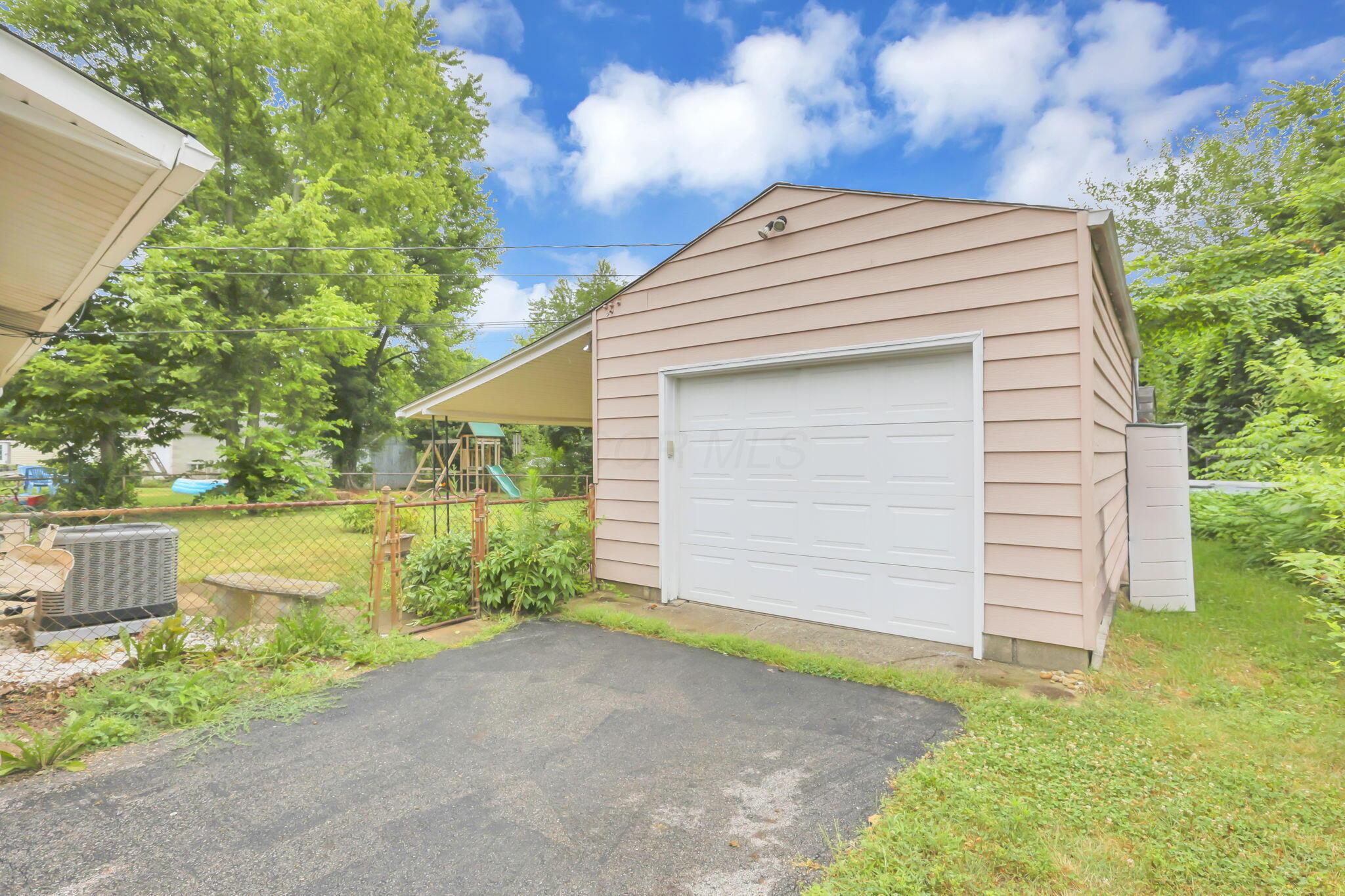 3882 Glenfield Road Columbus, OH 43232 - Photo 29 of 29 Detached garage with horizontal siding, a white overhead door, and an attached carport, providing covered parking