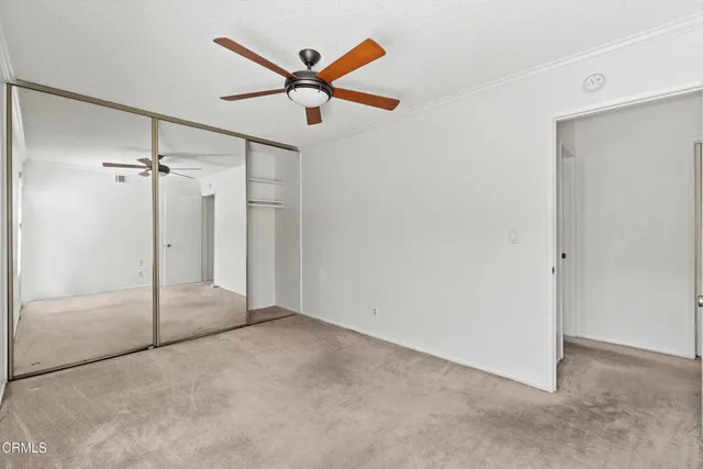 a view of a big room with a chandelier fan and closet area