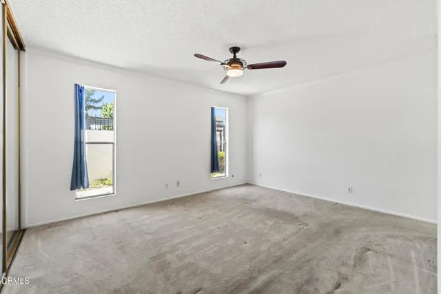 an empty room with windows and fan