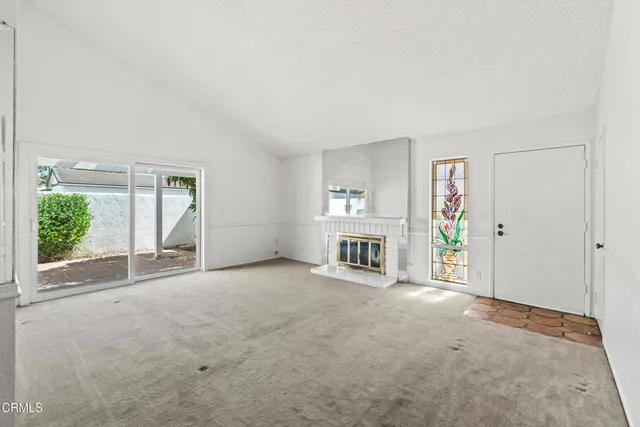 an empty room with windows and fireplace