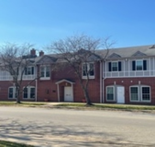 a front view of a building with a garden and mountain view