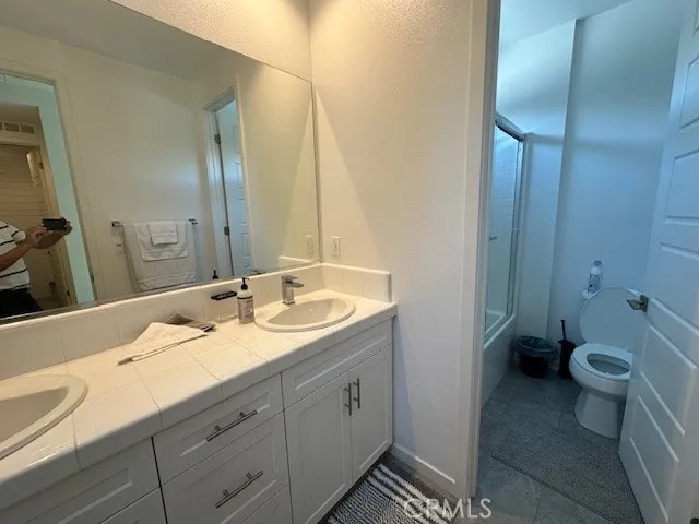 a bathroom with a granite countertop sink a toilet and a mirror