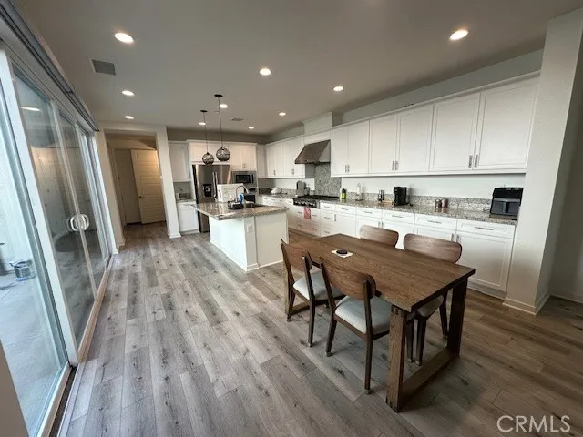 an open kitchen with kitchen island wooden floor and stainless steel appliances