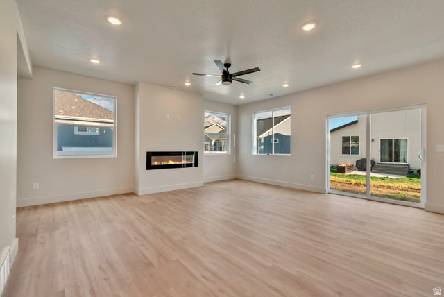 2535 West Santa Fe Drive Mapleton, UT 84664 - Photo 7 of 26 Unfurnished living room with a glass covered fireplace, light wood-type flooring, a ceiling fan, and recessed lighting