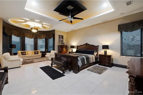 a spacious bedroom with a bed a chandelier and a large window