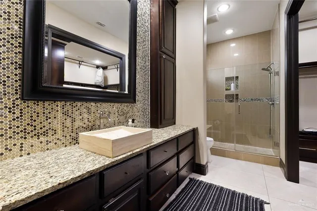 a bathroom with a granite countertop sink a mirror and shower