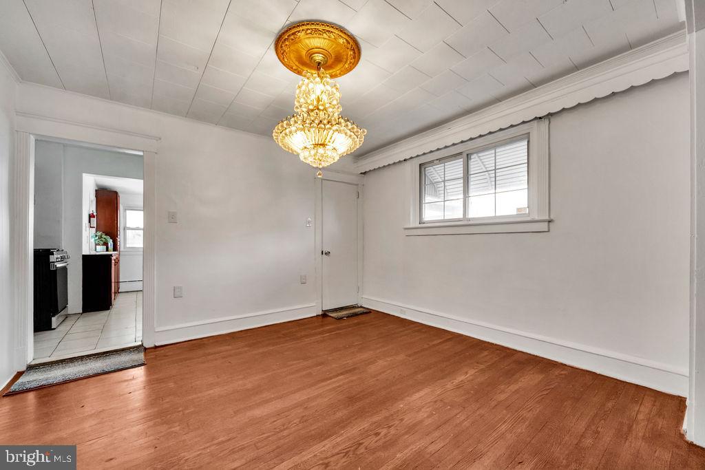 212 Heather Road Upper Darby, PA 19082 - Photo 11 of 28 an empty room with wooden floor and chandelier