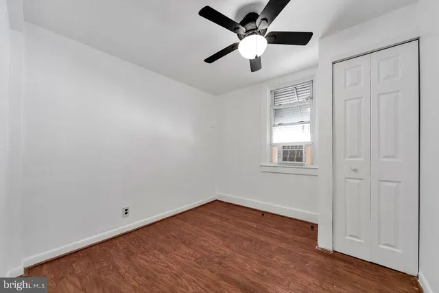an empty room with wooden floor closet and windows