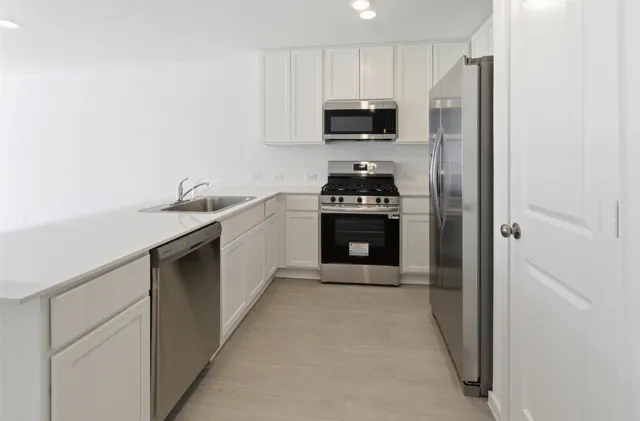 a kitchen with stainless steel appliances granite countertop a stove a sink and a refrigerator