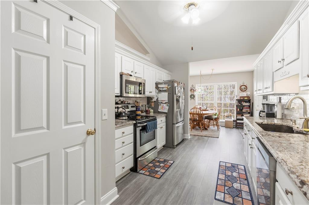 3724 Lexington Court Gainesville, GA 30504 - Photo 13 of 56 a kitchen with stainless steel appliances granite countertop a refrigerator oven stove and white cabinets with wooden floor