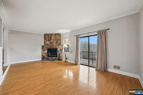 an empty room with wooden floor fireplace and windows