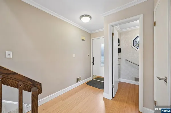 a view of a hallway with wooden floor and bathroom
