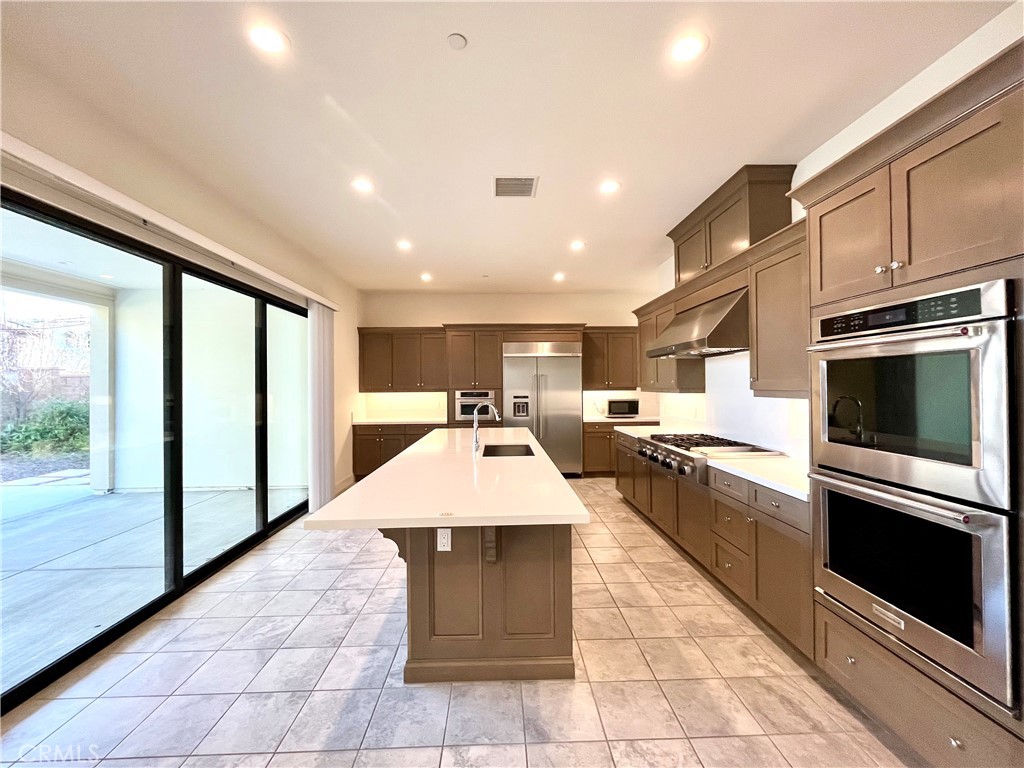 12040 Estrella Place Porter Ranch, CA 91326 - Photo 3 of 25 a large kitchen with stainless steel appliances granite countertop a large counter top a stove a sink dishwasher and a microwave oven with large trees