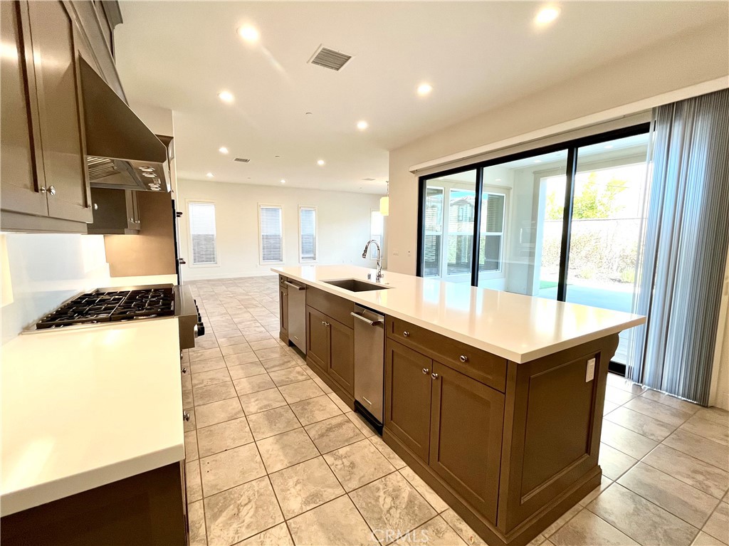 12040 Estrella Place Porter Ranch, CA 91326 - Photo 4 of 25 a large kitchen with kitchen island a large counter top space a sink stainless steel appliances and a large window