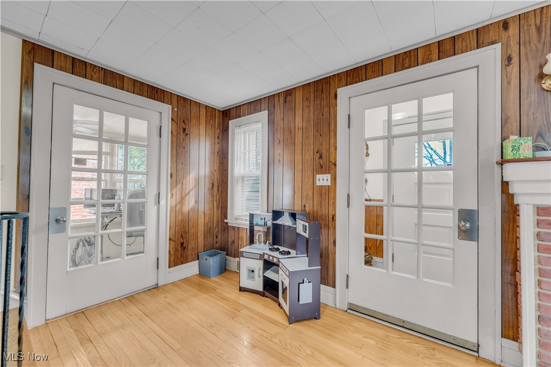 3729 Grosvenor Road Cleveland, OH 44118 - Photo 15 of 39 Doorway to outside with baseboards, light wood-style flooring, and wood walls