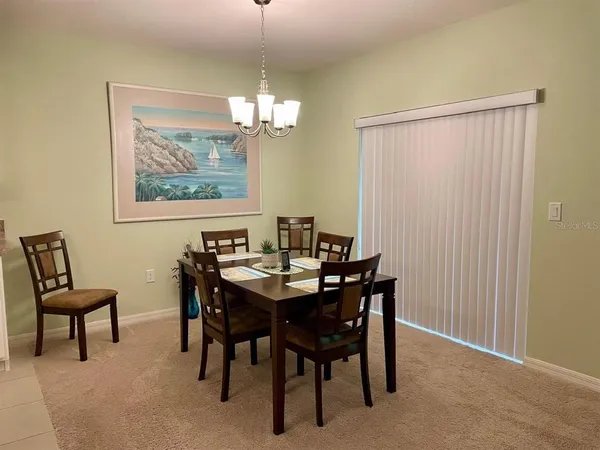 a view of a dining room with furniture a chandelier and a window