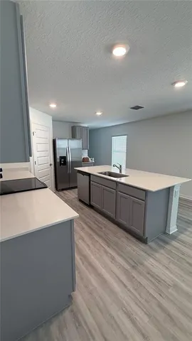 a large kitchen with kitchen island a sink dishwasher a stove and a refrigerator with wooden floor