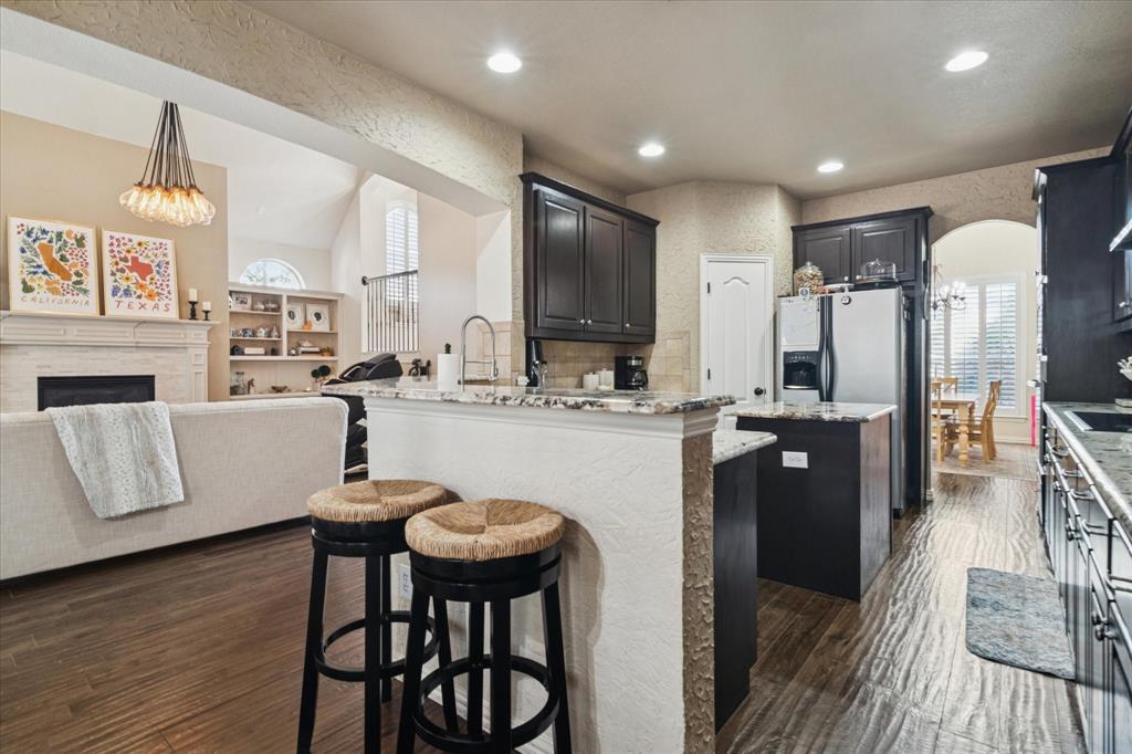 1602 Crown Point Road McKinney, TX 75072 - Photo 11 of 40 a kitchen with stainless steel appliances granite countertop a refrigerator a stove and a dining table with wooden floor