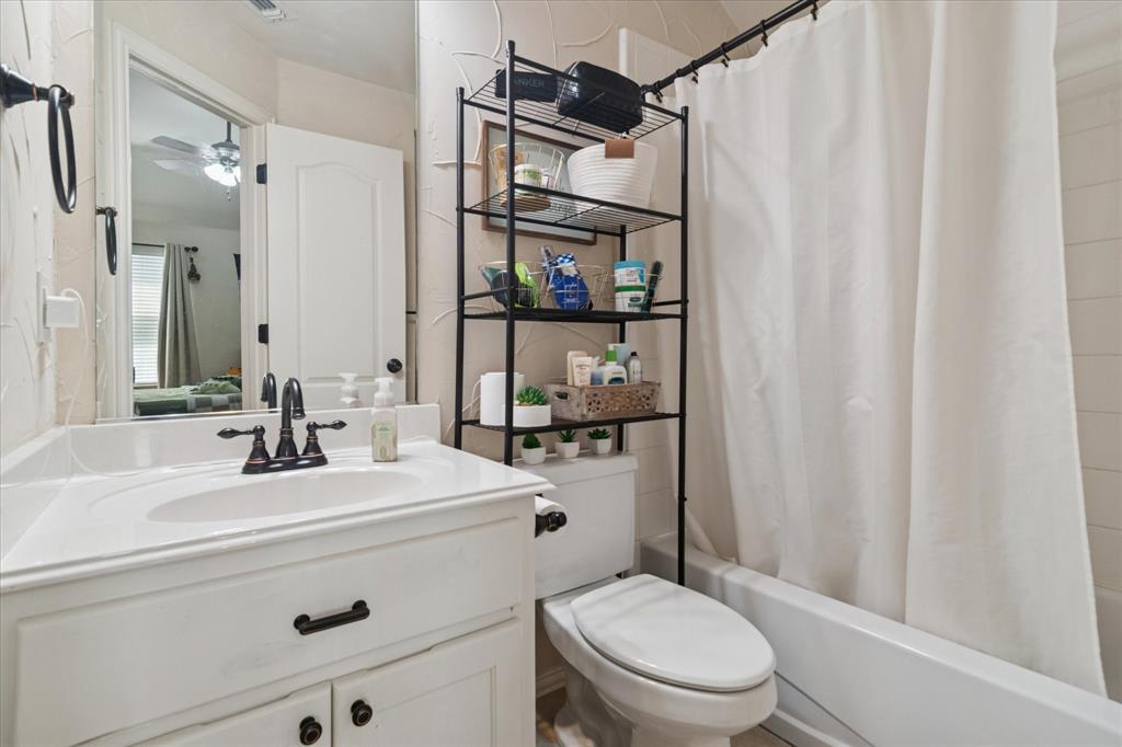 1602 Crown Point Road McKinney, TX 75072 - Photo 29 of 40 a bathroom with a sink a toilet a mirror and shower curtain