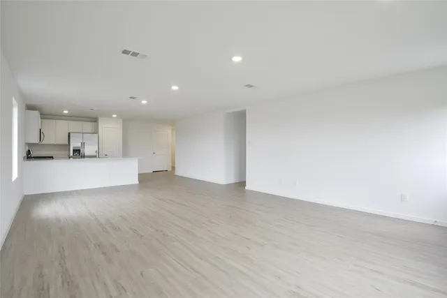 a view of a big room with wooden floor and a kitchen