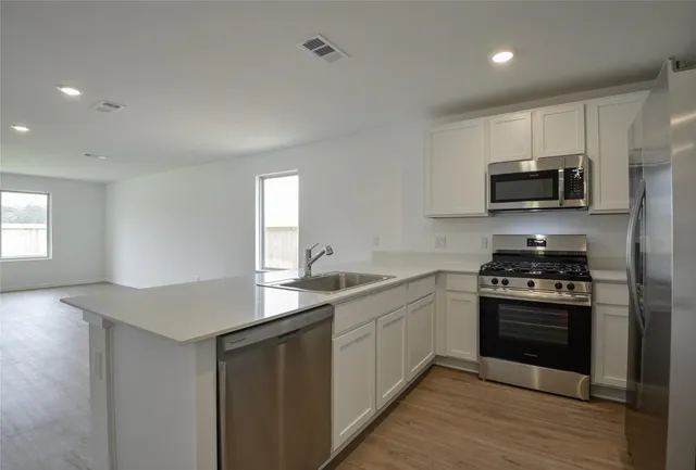 a kitchen with stainless steel appliances granite countertop a stove a sink and a microwave